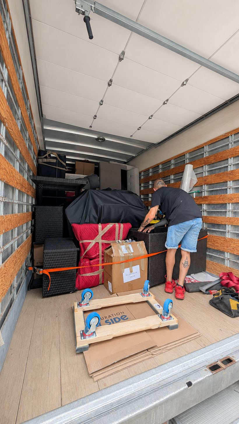 Intérieur du camion de Transports Dalpé : chargement sanglé aux rails latéraux, meubles enveloppés et plancher protégé par des cartons